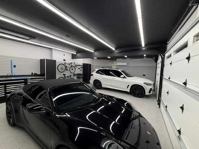 modern garage interior featuring a black sports car and a white SUV with sleek design elements