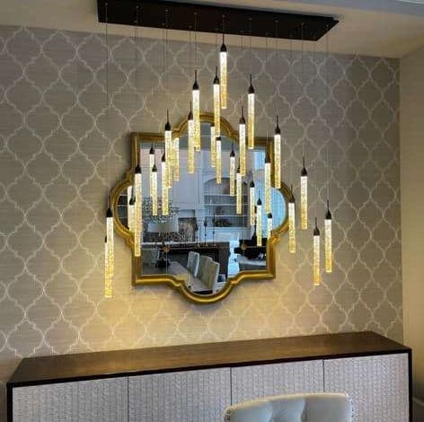 Chic modern chandelier with glass pendants above mirrored wall decor in stylish interior.
