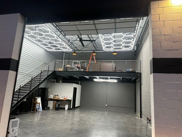 Modern industrial garage interior with mezzanine, open space, and bright hexagonal lights.