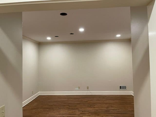 Empty room with hardwood floor, recessed lighting, and neutral wall color. Ideal for design projects.