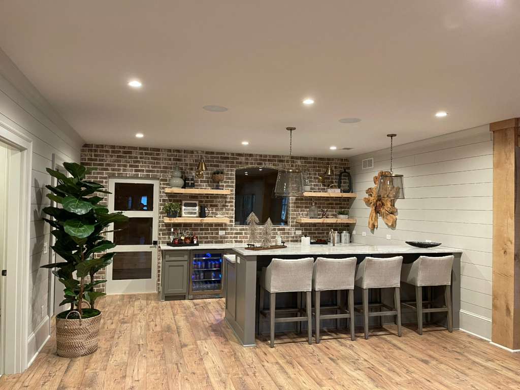 Modern kitchen with brick accent wall, bar seating, and large windows for natural light.