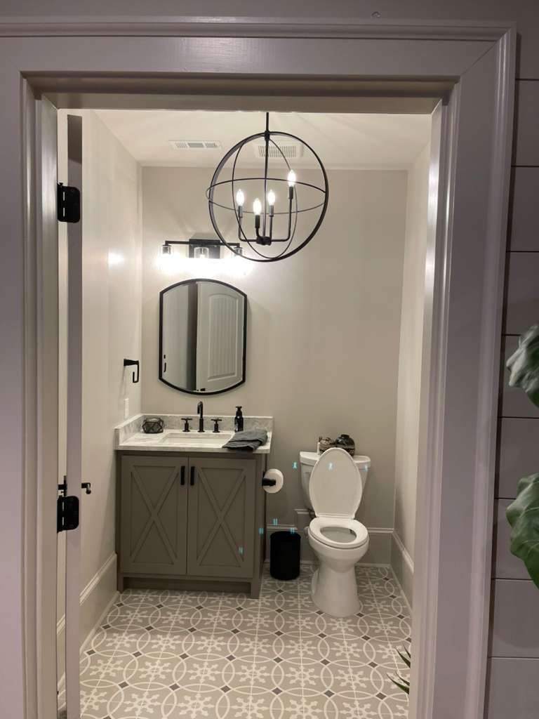 Modern bathroom with gray vanity, round mirror, and stylish lighting fixture.