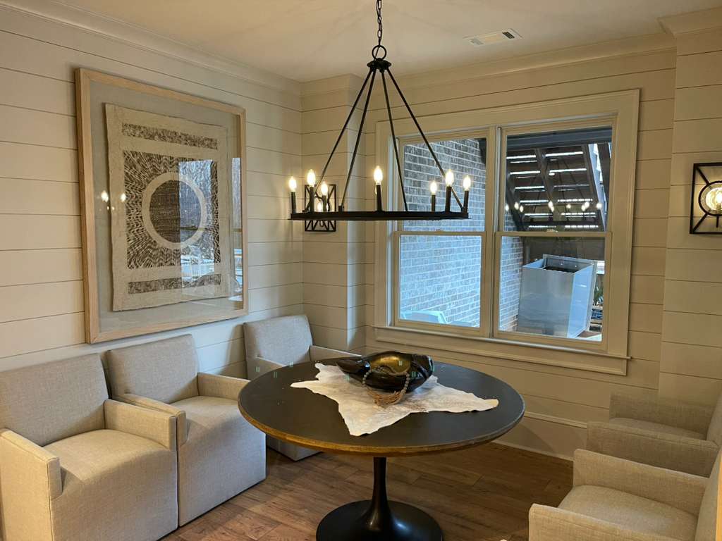 Modern dining area with a round table, stylish chandelier, and contemporary artwork.