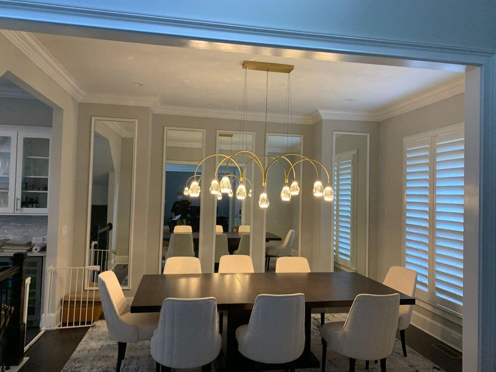 Modern dining room featuring a sleek chandelier and elegant white dining chairs.
