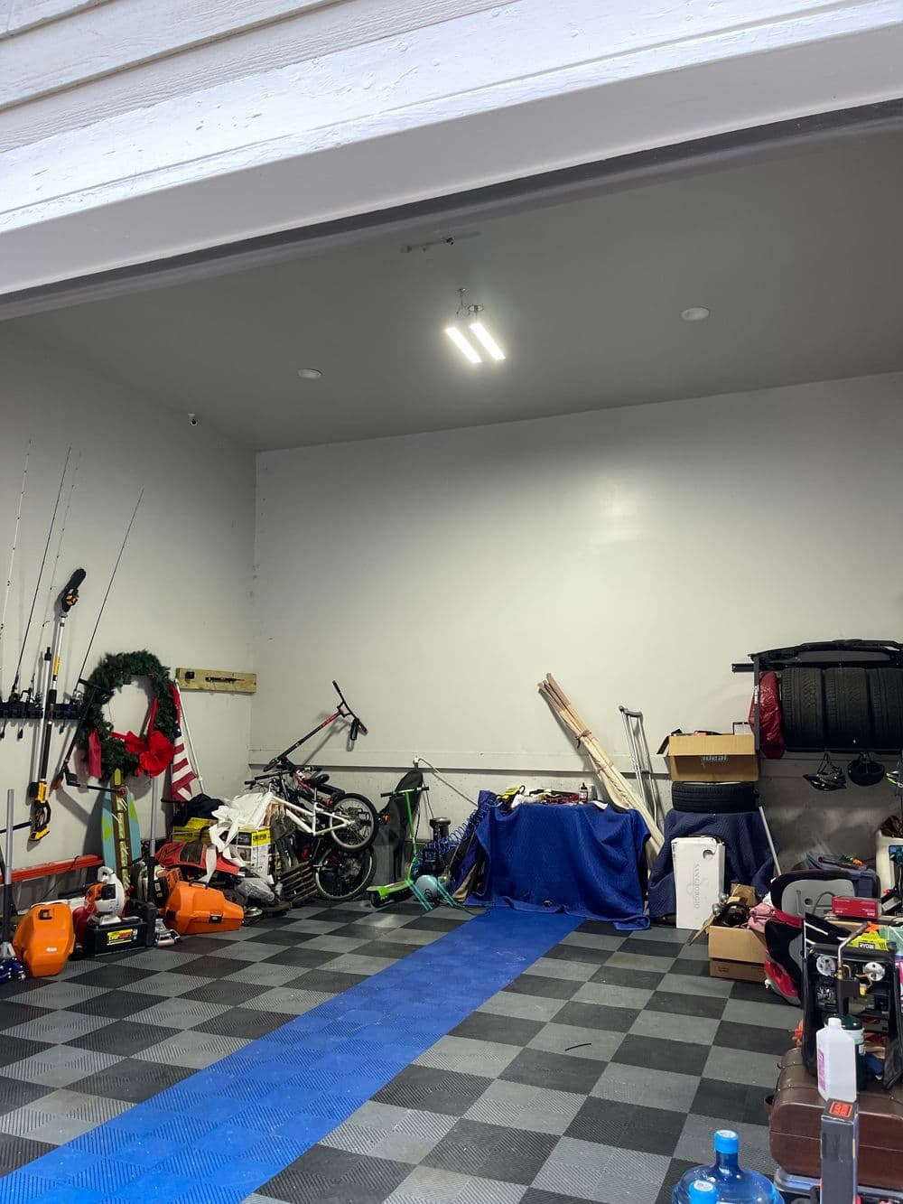 Garage interior with tools, bicycles, and organized storage on checkered flooring.
