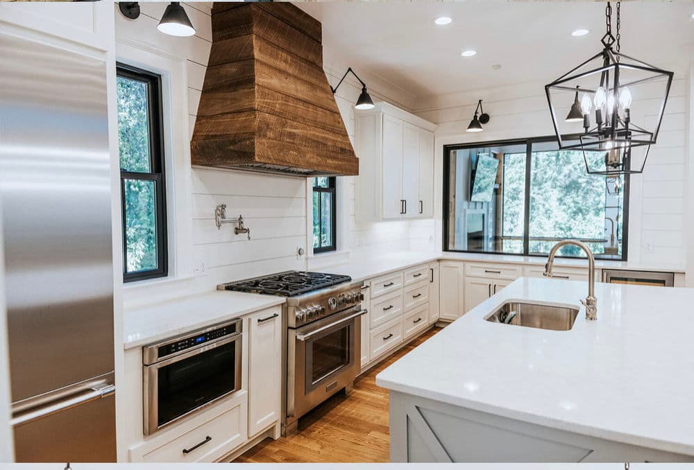 Modern kitchen with white cabinetry, wood accents, large island, and stainless steel appliances.